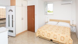 A bedroom with a bed, a wardrobe, a door, and an air conditioning unit. - Guest House Luce- Studio with Terrace and Garden View (Dubrovnik)