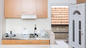 A modern kitchen with wooden cabinets, a stainless steel sink, a kettle, and a wine bottle. - Guest House Luce- Studio with Terrace and Garden View (Dubrovnik)