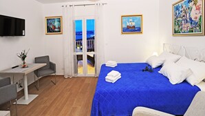 Une chambre d’hôtel avec un lit, un bureau, une chaise, une télévision et un balcon avec vue.