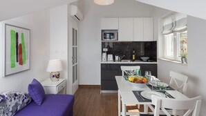 A compact living space with a dining area, kitchenette, and a bed with a purple pillow. - Amorino of Dubrovnik Apartment - Two Bedroom Apartment with Terrace and Sea View (Apartment Ruzmarin) (Dubrovnik)