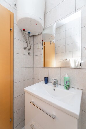 Une salle de bain avec un lavabo blanc, un miroir, un porte-serviettes et des toilettes.