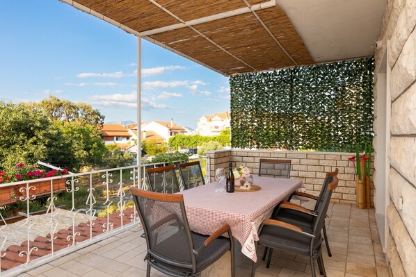 Un balcon avec une table et des chaises, une pergola et une vue sur le quartier.