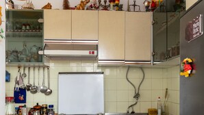 Eine kleine Küche mit Herd, Backofen und Spüle. Über der Spüle befinden sich Schränke und rechts ein Kühlschrank.