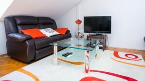 Ein modernes Wohnzimmer mit einer Ledersofa, einem Glastisch und einem Flachbildfernseher.