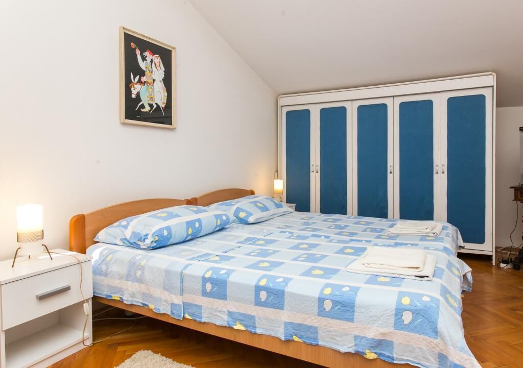 Une chambre à coucher avec un lit, une table de chevet, une armoire et un tableau au mur.