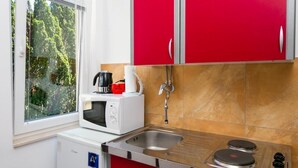 Eine kleine Küche mit Mikrowelle, Kaffeemaschine und Gasherd.