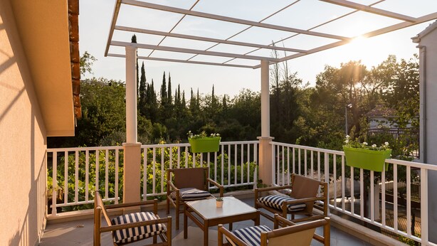 A covered outdoor patio with wooden furniture and white railings.