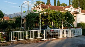 A house with a car parked in front, surrounded by a white fence.