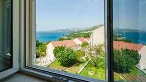 A view from a window overlooking a coastal area with houses, greenery, and the sea. - Villa Panorama Dubrovnik - Comfort One Bedroom Apartment with Balcony and sea View (Mlini)