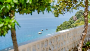 A coastal view with a stone balustrade, clear blue sea, and rocky outcrops.