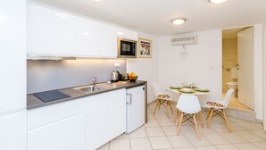 Eine moderne Küche mit weißen Schränken, einer eingebauten Mikrowelle und einem Essbereich mit Tisch und Stühlen.