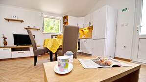 A compact kitchen with a dining area, a television, and a window providing natural light. - Apartments Memunić - Standard One Bedroom Apartment with Partial Sea View (Ston)