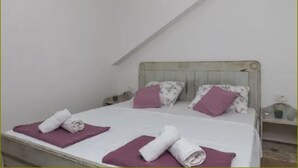 Una camera da letto con due letti, ognuno con un cuscino viola e un asciugamano arrotolato.