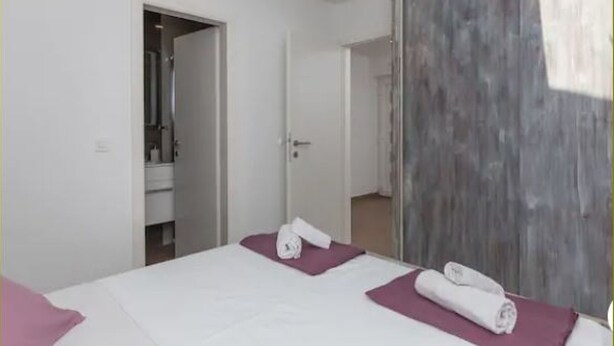 Una camera d'albergo con due letti, un bagno e una porta in legno.