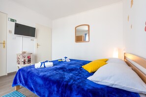 Una camera d'albergo con un letto, una televisione a parete, uno specchio e un armadio.