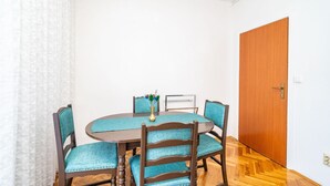 A dining area with a round table, four chairs, and a vase with flowers. - Apartments Peco - Four Bedroom Apartment with Balcony and Sea View (Mokosica)