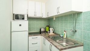 A kitchen with white cabinets, a microwave, a toaster, a kettle, and a sink. - Apartments Peco - Four Bedroom Apartment with Balcony and Sea View (Mokosica)