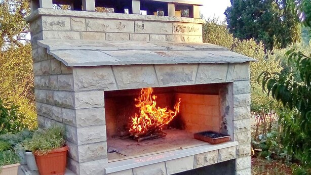 Una chimenea de piedra en el exterior, con fuego encendido.