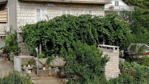 Un edificio con techo de tejas, fachada de piedra y un jardín con plantas y un sendero.