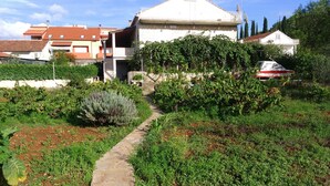 Un sendero jardín que lleva a una casa con techo inclinado y antenas parabólicas.