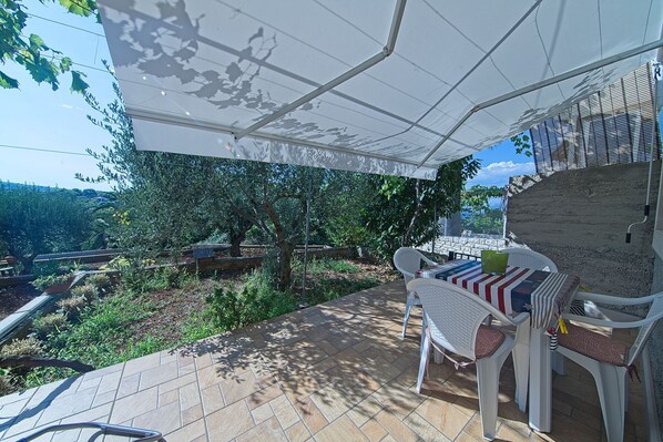 An outdoor patio with a table and chairs, a pergola, and a view of the surrounding landscape. - Apartment Alva - Two Bedroom Apartment with Terrace (Splitska)