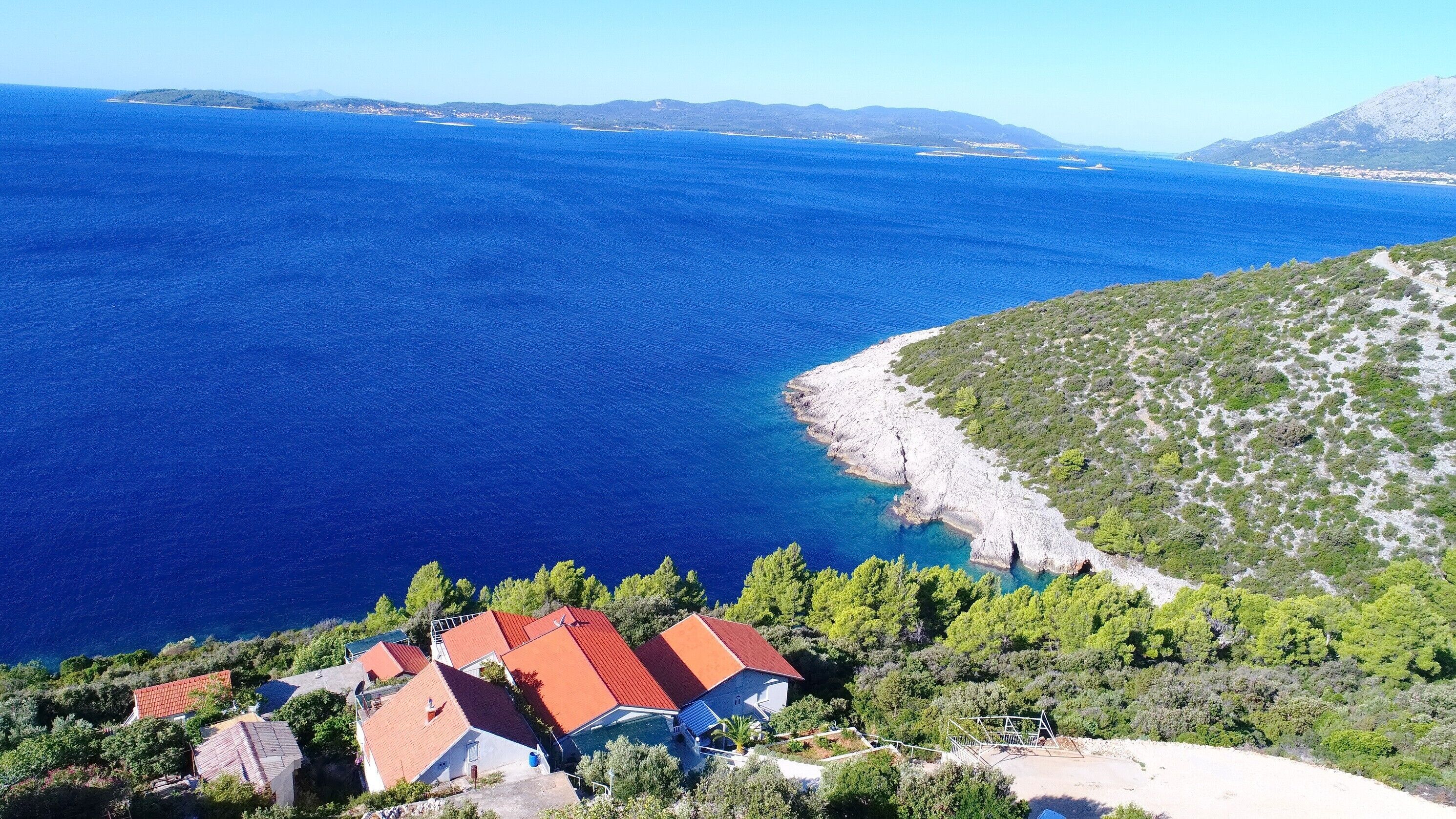 Una propiedad costera con vista al mar, un litoral rocoso y un grupo de casas con tejados rojos.