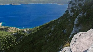 Paesaggio montuoso con vista chiara su un'ampia distesa d'acqua e colline lontane.
