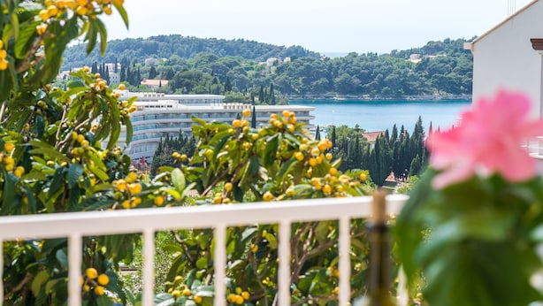 A balcony with a view of a coastal area, including a building with a curved facade and a body of water.