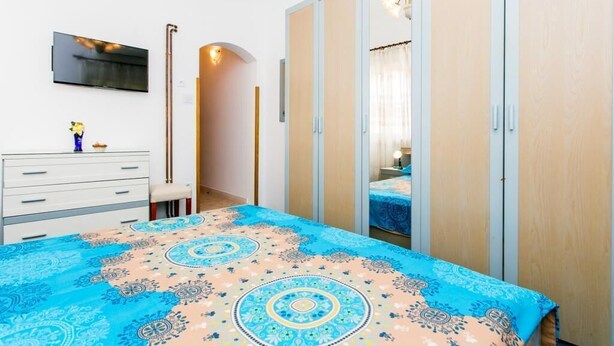 Een slaapkamer met een bed, een kledingkast, een bureau en een televisie.