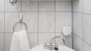 Een badkamer met een wit wastafelmeubel, een handdoekhouder, een spiegel en een zeepdispenser.