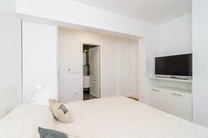 Ein modernes Schlafzimmer mit Bett, Fernseher auf einem Schrank und begehbarer Kleiderschrank.