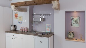 A compact kitchen with a wooden beam ceiling, a built-in sink, and a compact dishwasher.