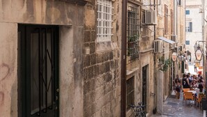 A narrow cobblestone street with historic buildings, a black door, and a bicycle parked outside.