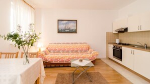 Ein gemütliches Wohnzimmer mit einer Couch, einem Esstisch und einer Küchenzeile mit Schränken und einem Herd.