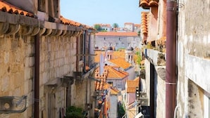 Eine enge Straße mit Gebäuden, die Terrakotta-Dächer und steinernes Mauerwerk haben.