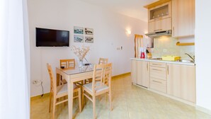 Eine kleine Küche mit Holzausstattung, einem eingebauten Backofen und einem flachbildfernseher an der Wand.