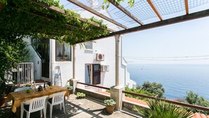A terrace with a table and chairs, potted plants, and a view of the sea. - Apartment Gigi - Two Bedroom Apartment with Terrace and Sea View (Dubrovnik)