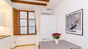 A modern kitchen with white cabinets, a wooden ceiling, and a window with curtains.