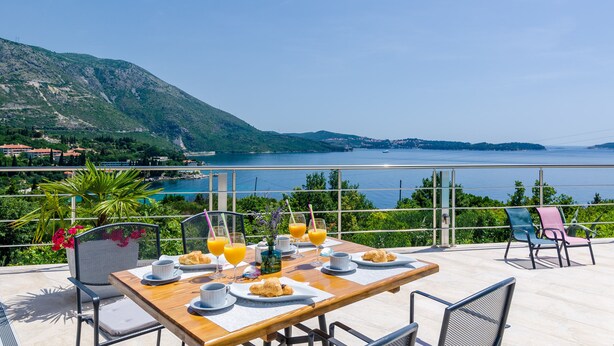 A table set with breakfast items and drinks overlooking a scenic coastal view.