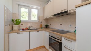 A modern kitchen with white cabinets, a built-in oven, and a window providing natural light.