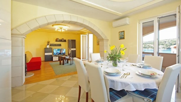 Un comedor con una mesa dispuesta para cuatro personas, un sofá rojo y una cocina al fondo.
