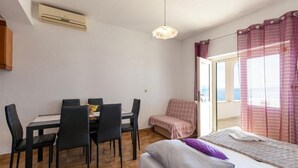 A compact room with a bed, a dining table with chairs, a small sofa, and a window with curtains. - Apartments Nena (ST) - One Bedroom Apartment with Terrace and Sea View (Pisak)