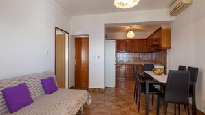 A compact living space with a sofa, dining table, chairs, and a kitchenette. - Apartments Nena (ST) - One Bedroom Apartment with Terrace and Sea View (Pisak)