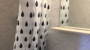 Een badkamer met een wit wastafel, een spiegel en een douchegordijn met zwarte druppelmotieven.