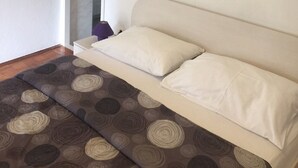 Een kamer met een beige bank, een kamerbreed tapijt met patroon en een airconditioning.