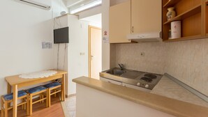 Uma cozinha compacta com fogão, pia e uma pequena mesa de jantar com bancos.