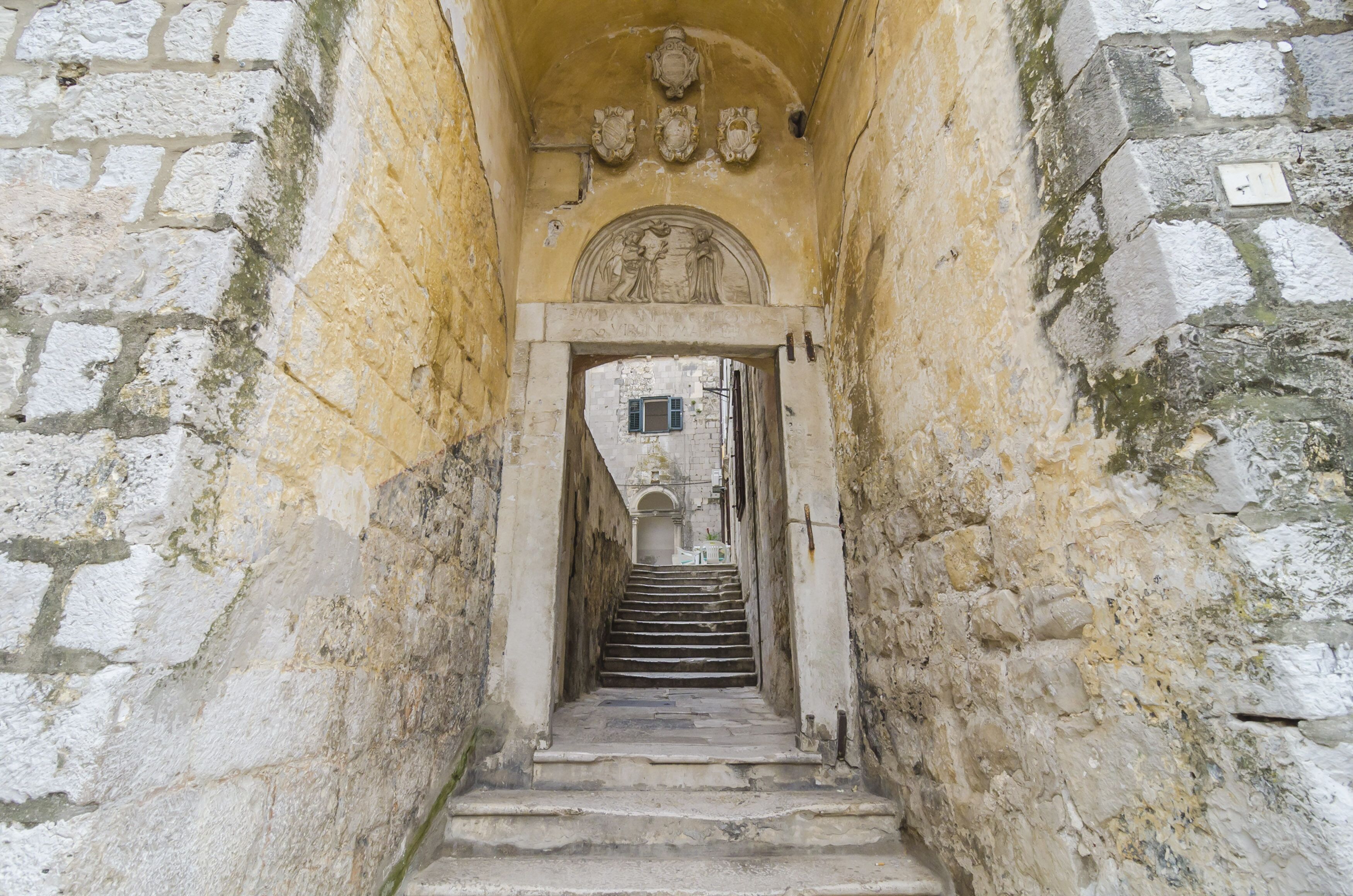A narrow stone staircase leading to a doorway with a decorative arch.