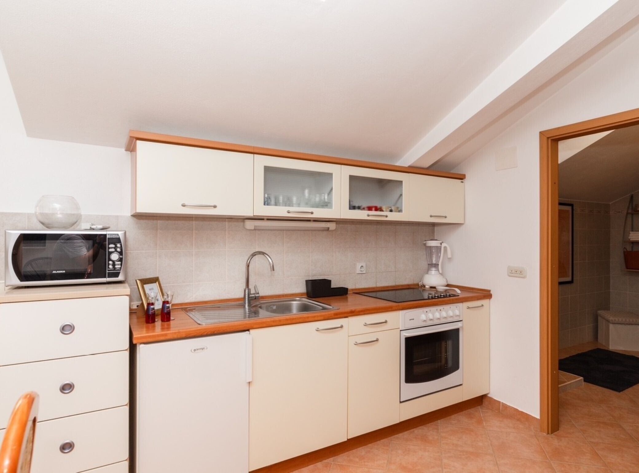 A compact kitchen with a microwave, sink, stove, and cabinets.