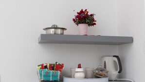 A kitchen area with shelves holding various kitchen items, a coffee maker, and a kettle. - Room Primi - Double Room with Terrace (Dubrovnik)