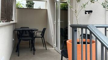 Ein Balkon mit Tisch und Stühlen, einem Blumentopf und einer Glasschiebetür, die zu einem Innenbereich führt.